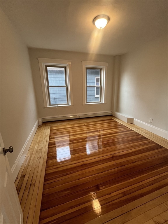 108 Bristol Road, Unit 1 Somerville, MA 02144 - Photo 19 of 30 a view of an empty room with wooden floor and a window