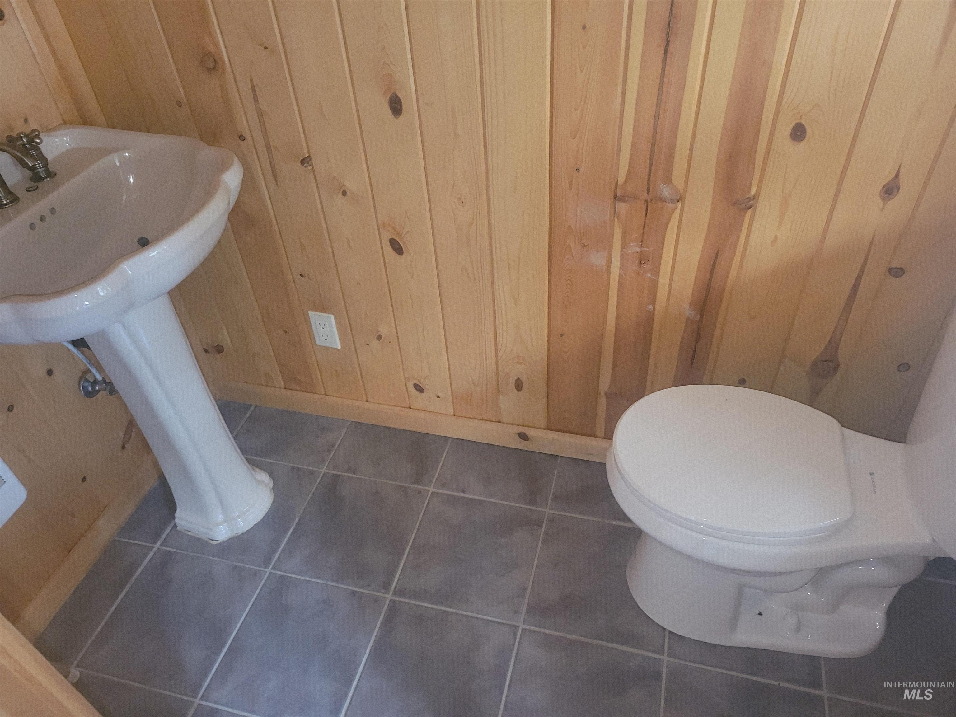 129 Copperhead Road Elk City, ID 83525 - Photo 11 of 28 Half bathroom featuring wood walls and dark tile patterned floors