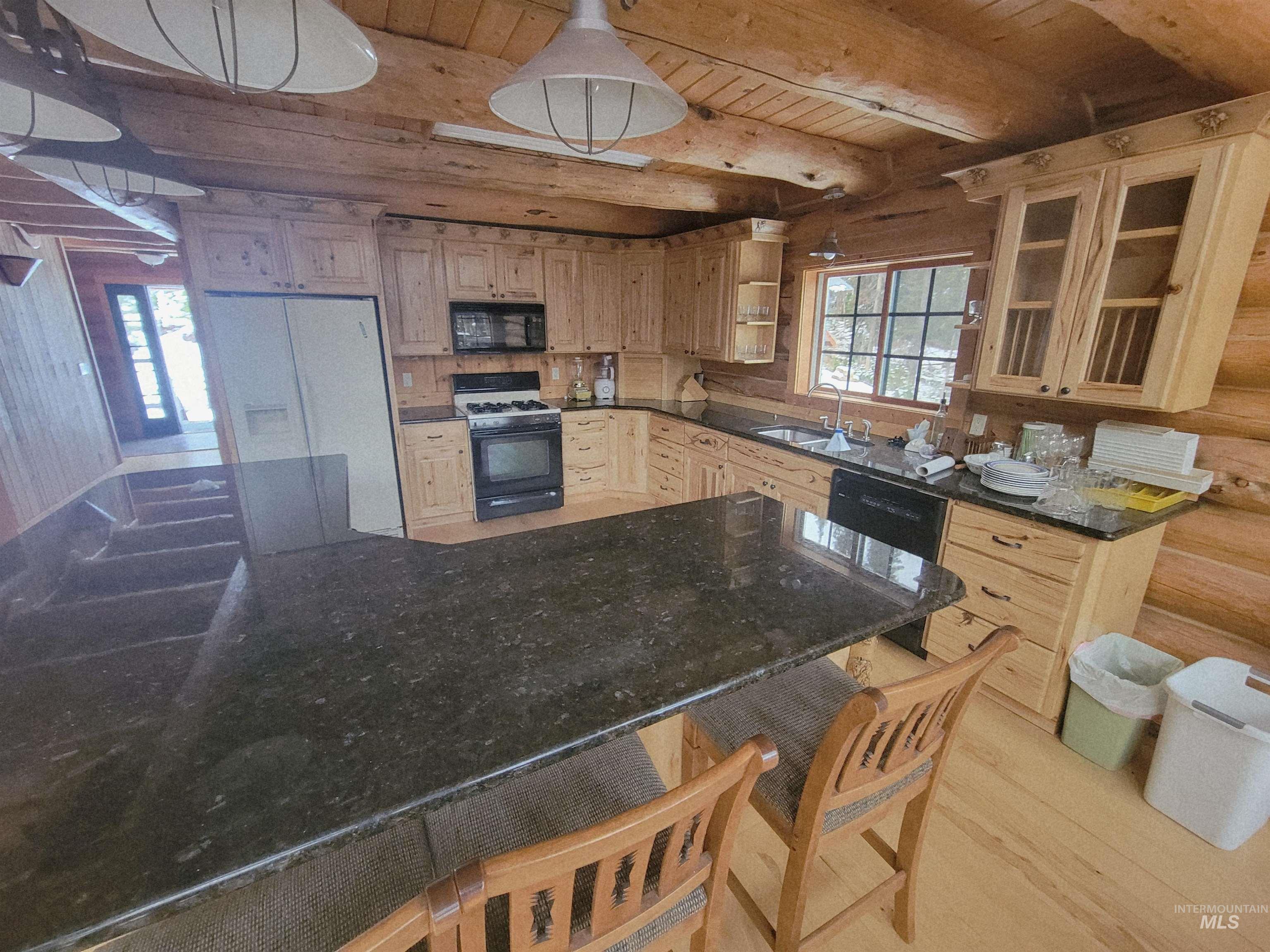 129 Copperhead Road Elk City, ID 83525 - Photo 13 of 28 Kitchen featuring a wood ceiling with exposed beams, black appliances, light wood-style flooring, light brown cabinetry, and glass insert cabinets