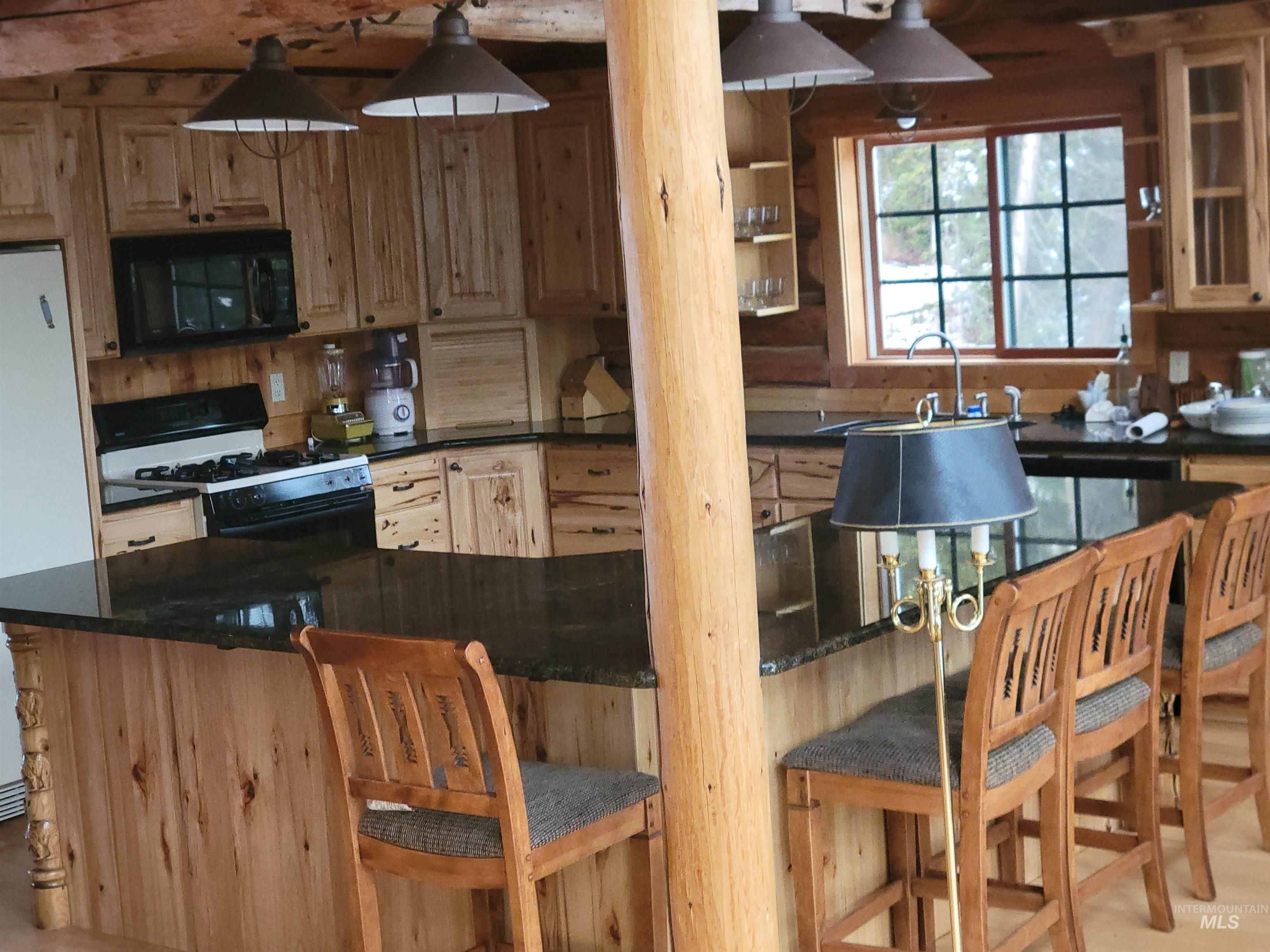 129 Copperhead Road Elk City, ID 83525 - Photo 17 of 28 Kitchen with black microwave, gas range oven, freestanding refrigerator, a kitchen bar, and dark stone counters