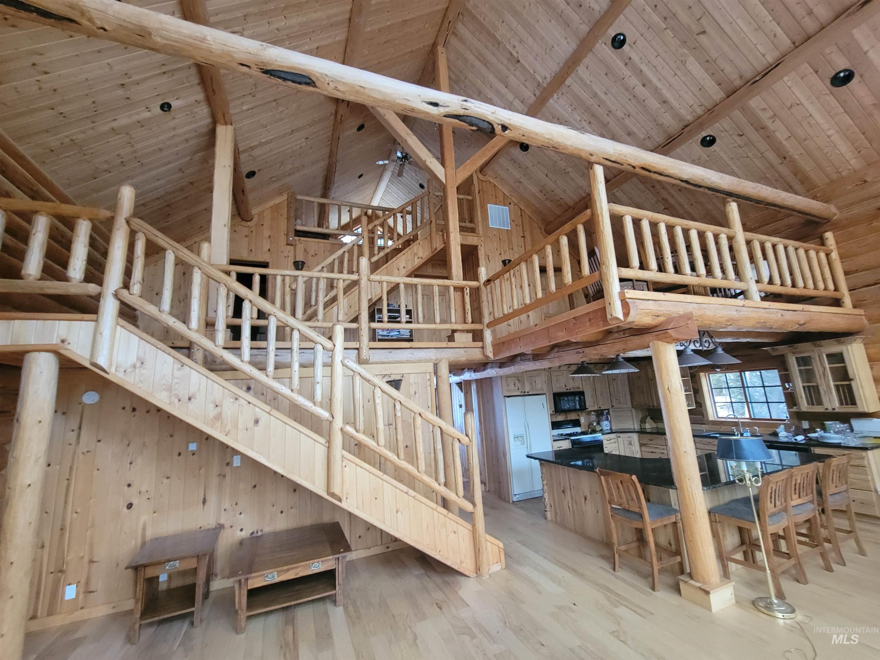 129 Copperhead Road Elk City, ID 83525 - Photo 18 of 28 Unfurnished living room with wooden walls, high vaulted ceiling, light wood-style flooring, a wooden ceiling with exposed beams, and stairway