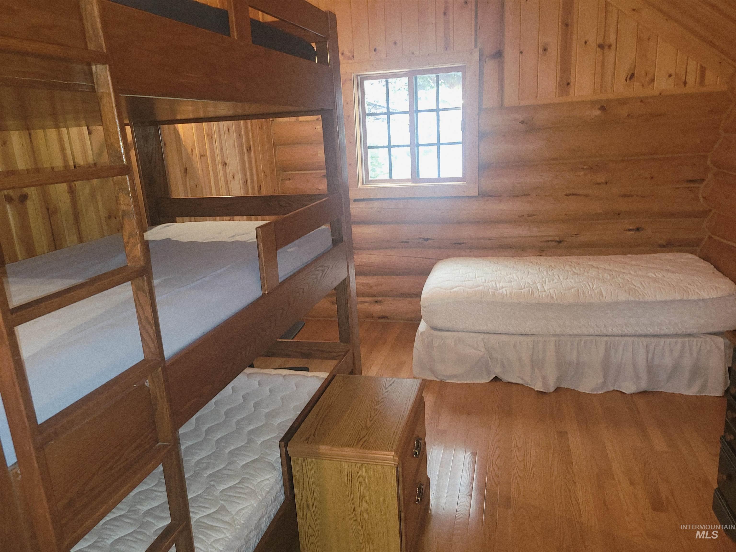 129 Copperhead Road Elk City, ID 83525 - Photo 23 of 28 Bedroom with light wood-type flooring, wooden walls, and rustic walls