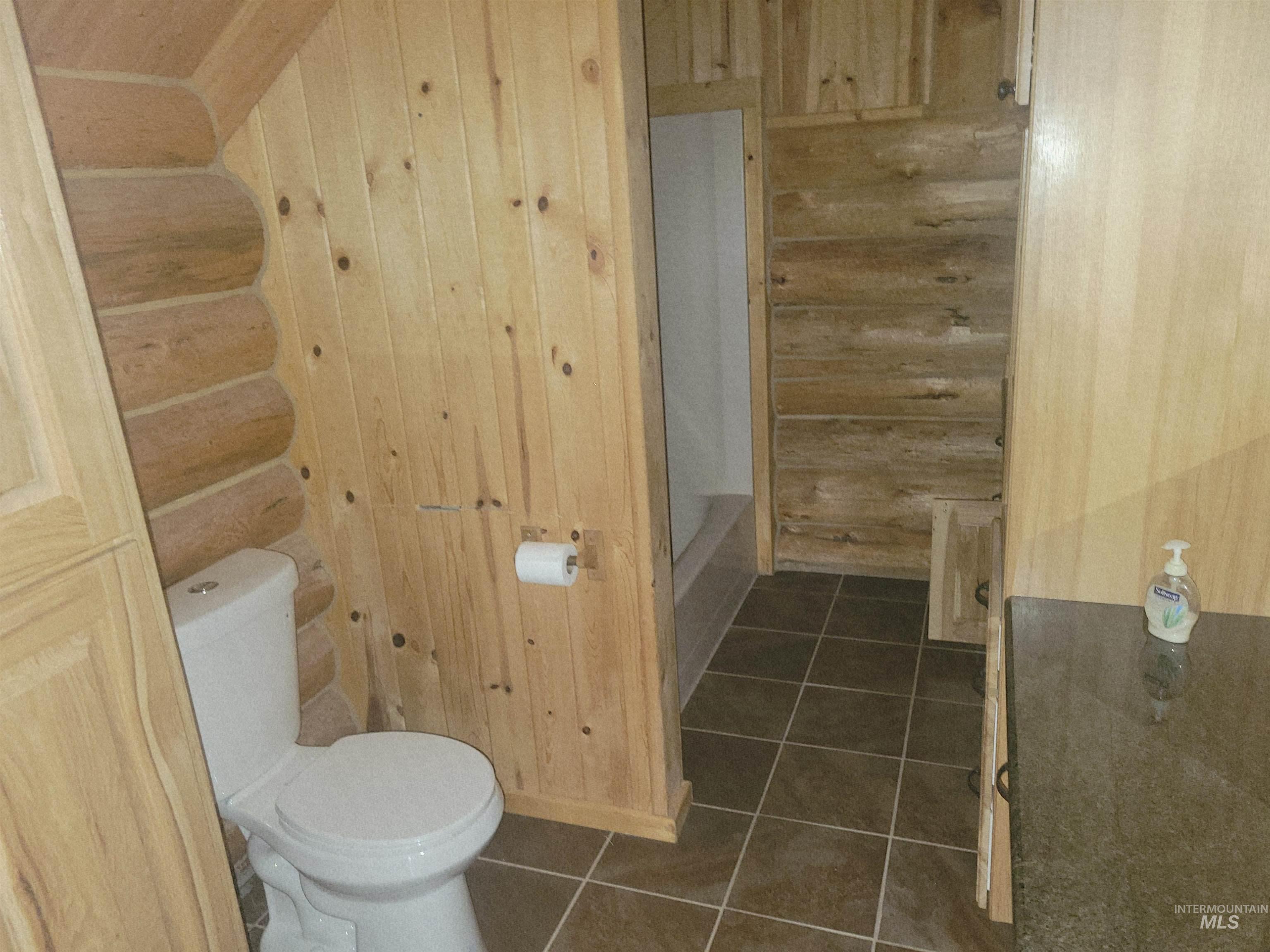 129 Copperhead Road Elk City, ID 83525 - Photo 25 of 28 Bathroom with dark tile patterned flooring, wooden walls, and bathtub / shower combination