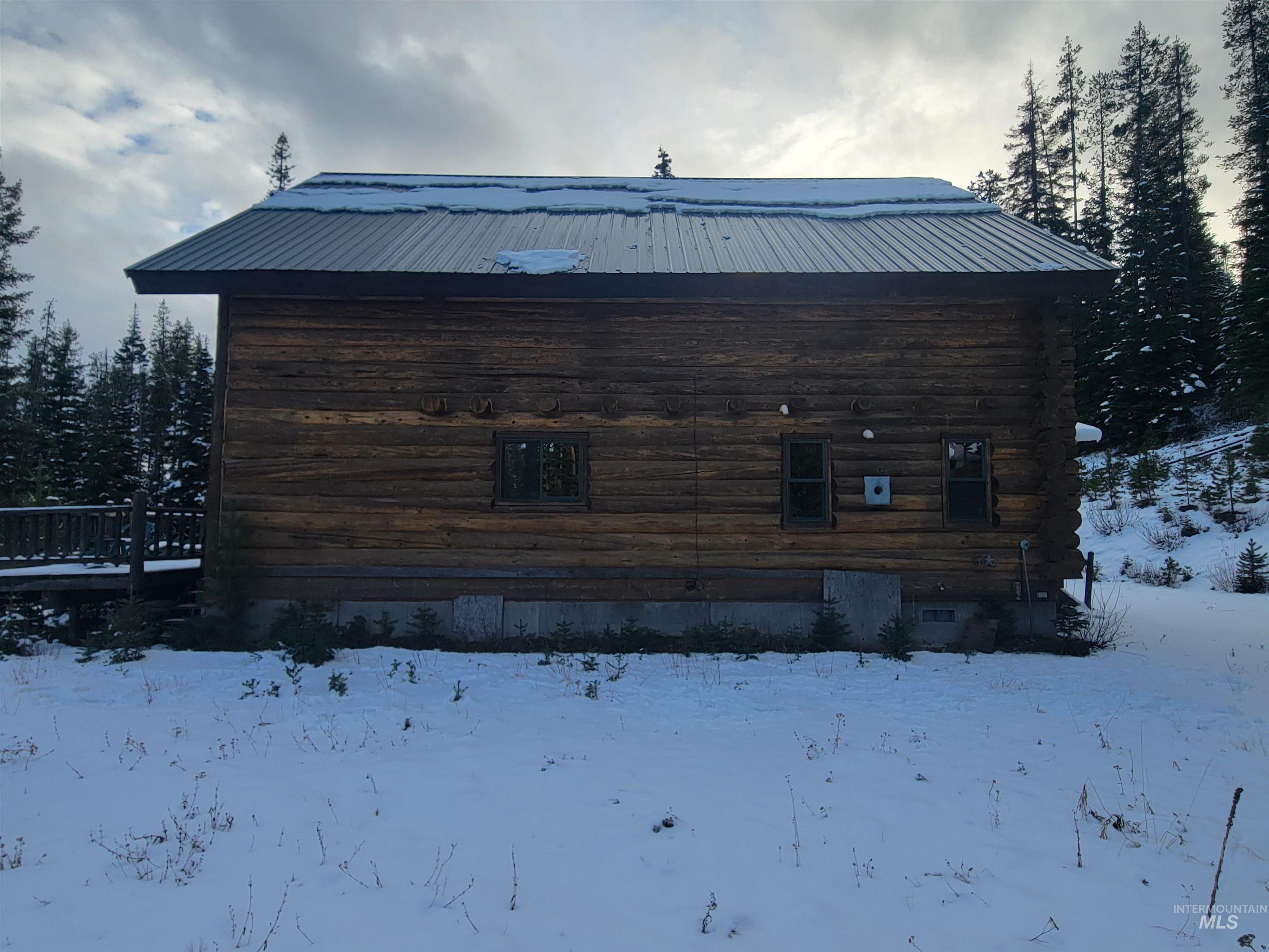 129 Copperhead Road Elk City, ID 83525 - Photo 7 of 28 Snow covered property featuring log siding, a metal roof, and a wooden deck