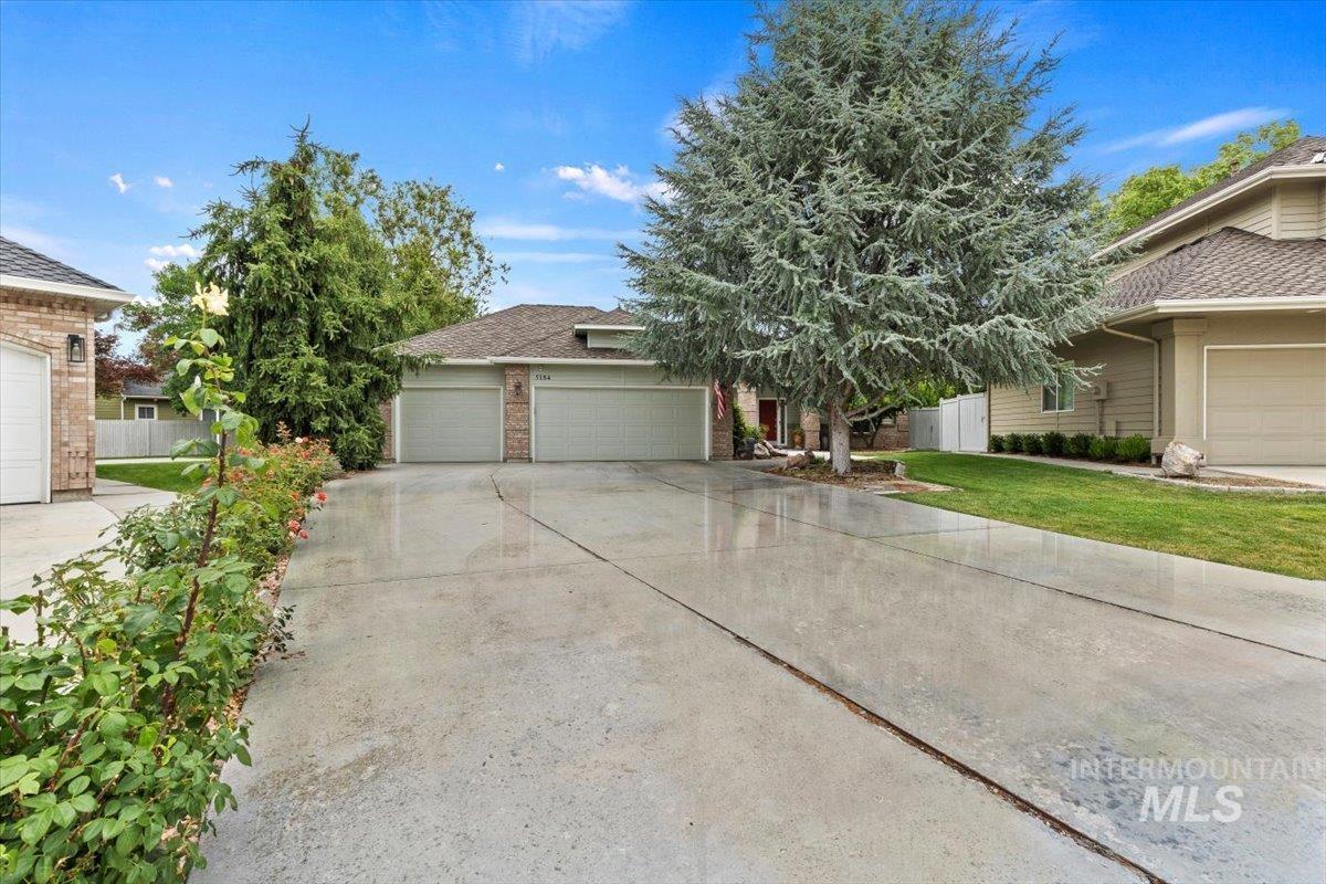5184 North Greyloch Way Boise, ID 83704 - Photo 2 of 32 Expansive concrete driveway with mature landscaping, a two-car garage, and a brick facade accent
