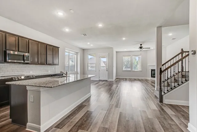 a kitchen with stainless steel appliances granite countertop a stove and a wooden floors