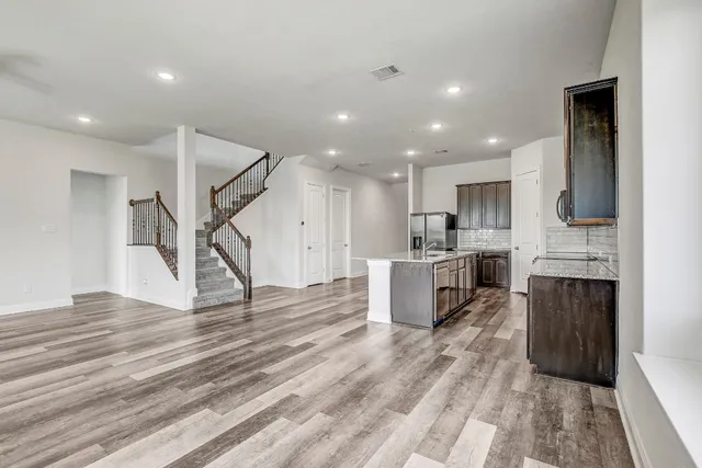 a open kitchen with kitchen island a refrigerator a stove a sink and a microwave oven with wooden floor