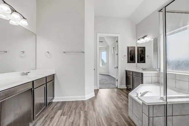 a spacious bathroom with a tub sink and mirror