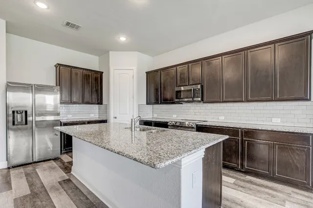 a kitchen with stainless steel appliances granite countertop a sink stove and refrigerator