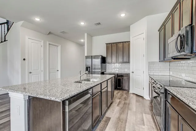 a kitchen with stainless steel appliances granite countertop a kitchen island a stove a sink and a refrigerator