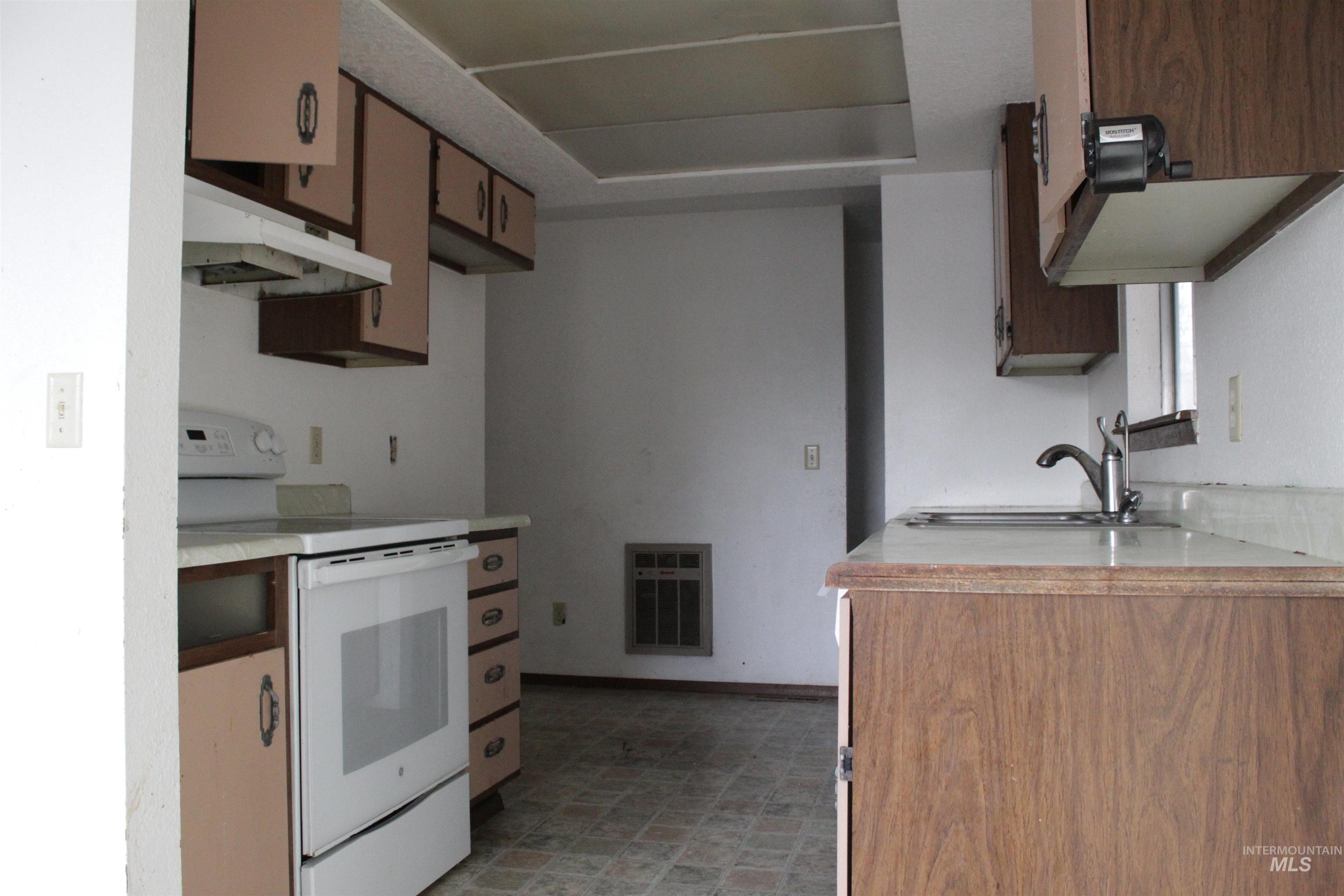 622 East Court Street Weiser, ID 83672 - Photo 9 of 20 Kitchen with electric range, light countertops, heating unit, light floors, and wood finish cabinetry