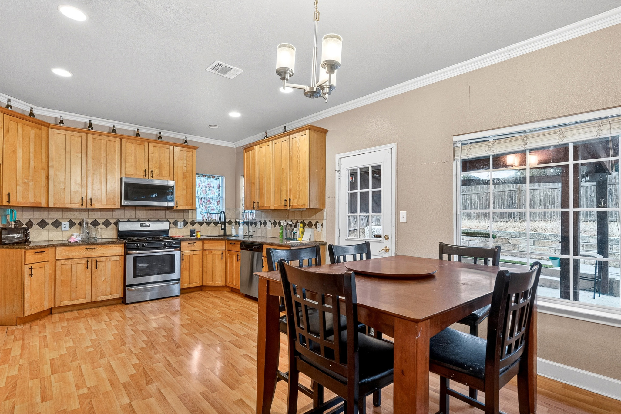 3811 Hawk View Street Round Rock, TX 78665 - Photo 4 of 20 a kitchen with stainless steel appliances granite countertop a stove top oven a sink dishwasher a dining table and chairs with wooden floor