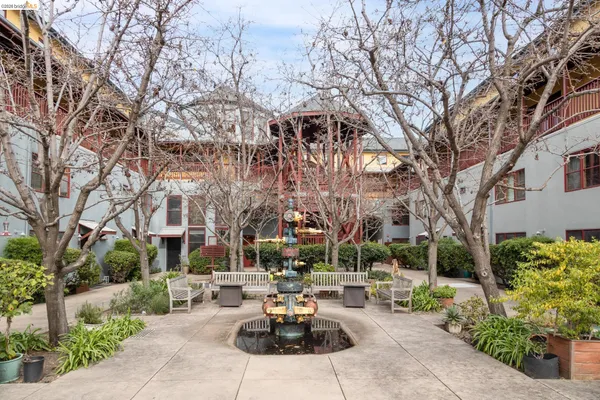 a view of a patio with couches and table and chairs under an umbrella with large trees