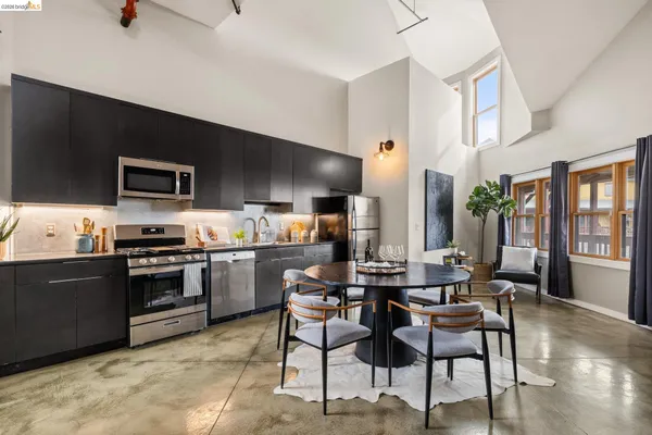 a kitchen with a stove a refrigerator and chairs