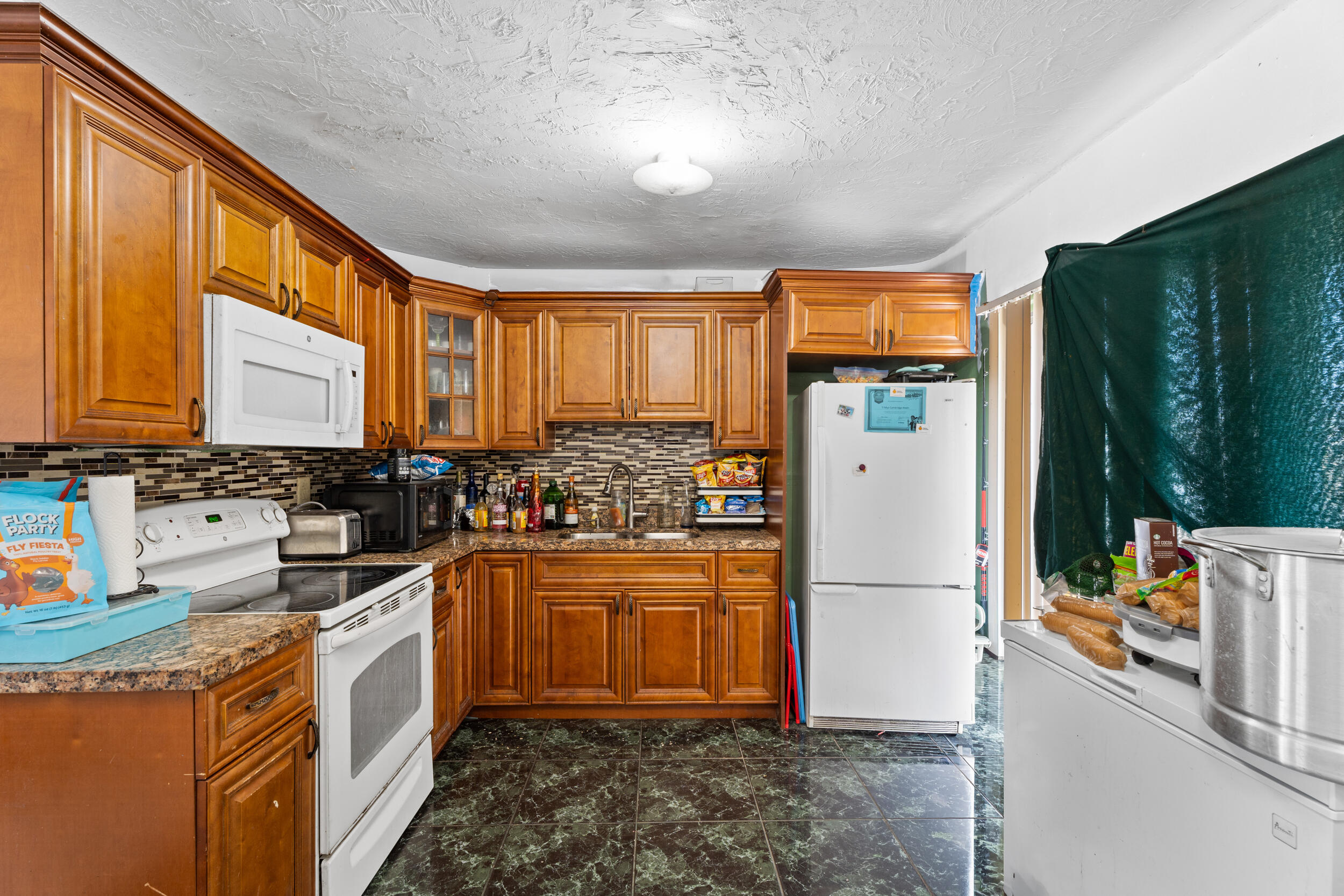 1449 West 35th Street Riviera Beach, FL 33404 - Photo 8 of 28 a kitchen with a refrigerator a stove top oven a sink and cabinets