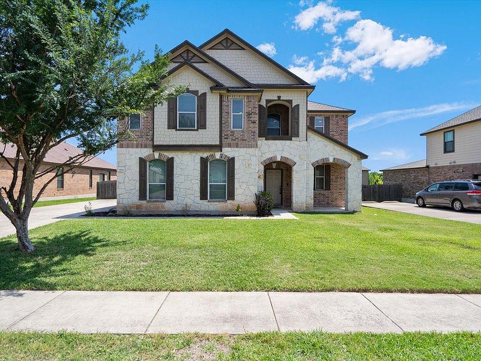 The property features an appealing exterior with brick and stone accents, complemented by decorative window shutters