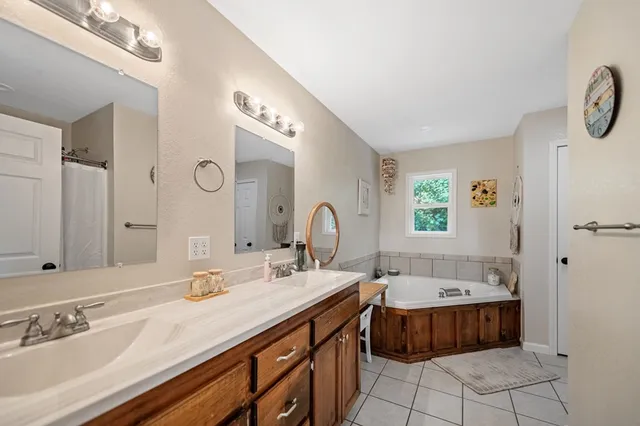 a spacious bathroom with a double vanity sink mirror and bathtub
