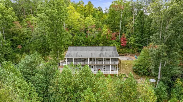 a aerial view of a house with yard and trees in the background