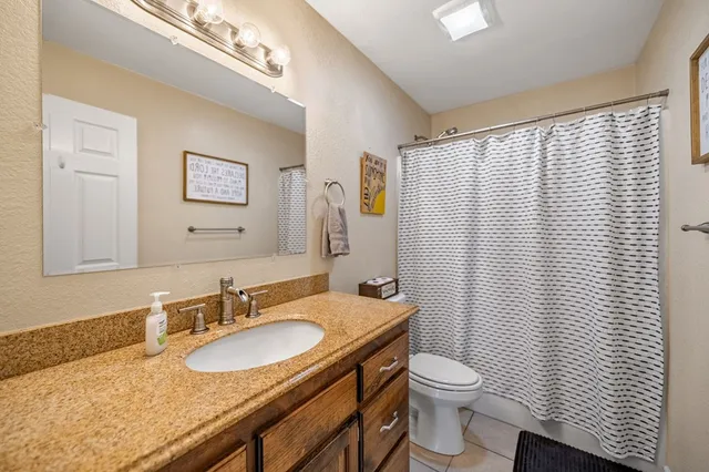 a bathroom with a granite countertop sink toilet and mirror