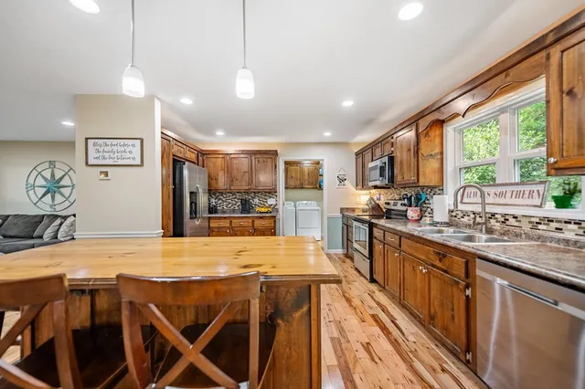 a large kitchen with kitchen island a large window a sink and appliances