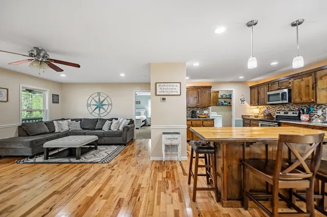 a living room with stainless steel appliances kitchen island granite countertop furniture and a wooden floor