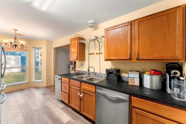 a kitchen with stainless steel appliances granite countertop a sink a stove and a wooden cabinets