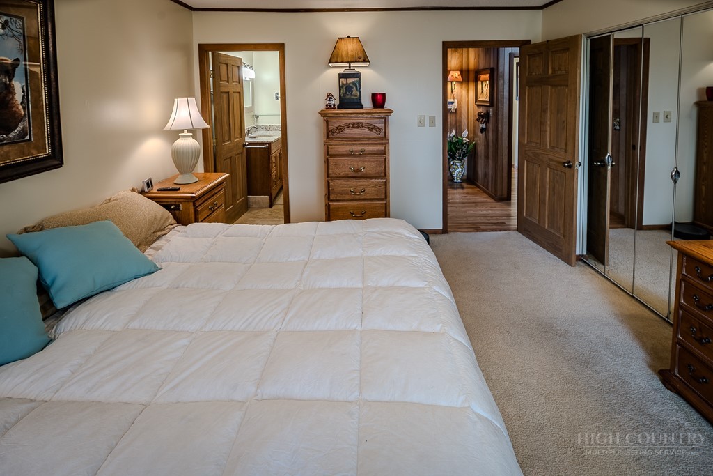 103-105 Upper Grouse Ridge Road Beech Mountain, NC 28604 - Photo 21 of 48 a bedroom with a bed and a chandelier