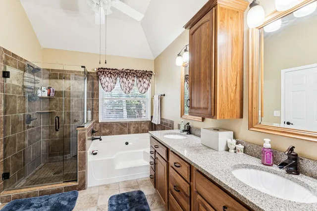 a bathroom with a granite countertop double vanity sink a mirror and a shower
