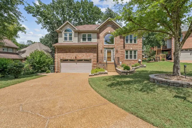 a front view of a house with a garden and trees