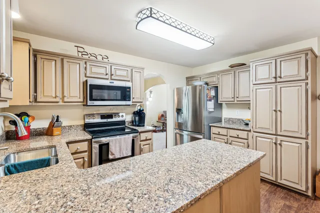 a kitchen with stainless steel appliances granite countertop a refrigerator stove microwave and sink