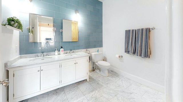 a spacious bathroom with a double vanity sink a mirror and a toilet