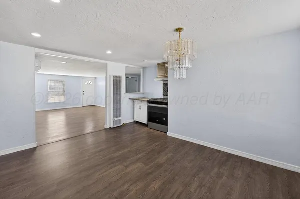 an empty room with wooden floor and kitchen view