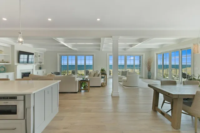 a living room with couches and kitchen view with wooden floor