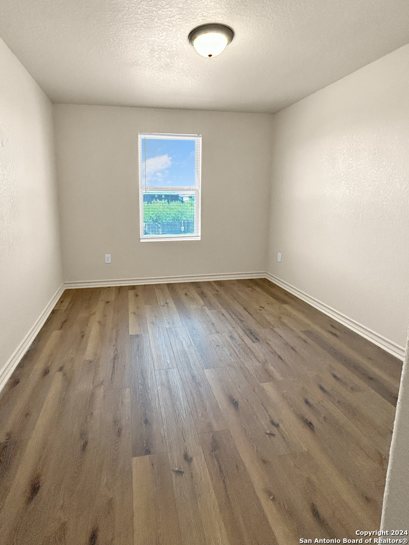 14006 Fratelli Road, Unit 103 San Antonio, TX 78233 - Photo 4 of 16 an empty room with wooden floor and windows