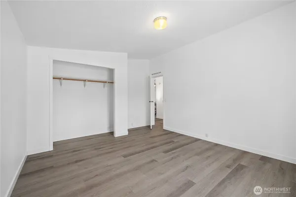 a view of an empty room with wooden floor and closet