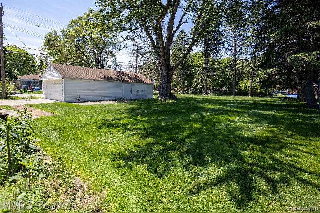 33033 Edgegrove Road Fraser, MI 48026 - Photo 4 of 20 Expansive green lawn with mature trees and a detached garage featuring two white garage doors