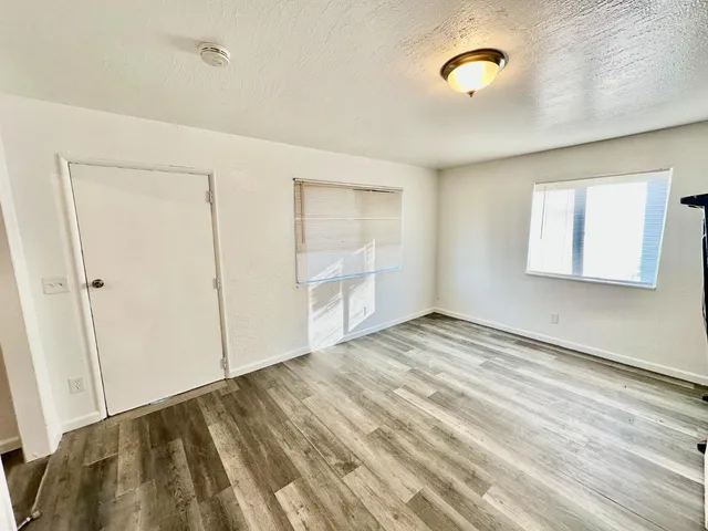 a view of empty room with wooden floor and fan