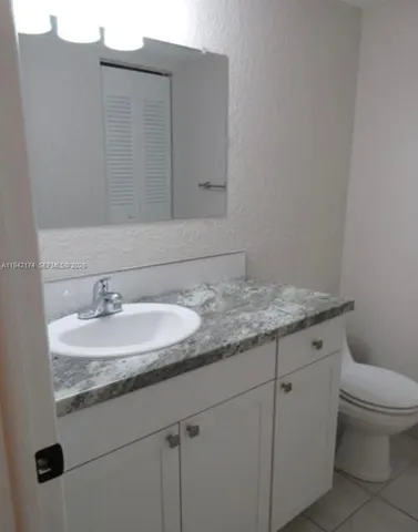 a bathroom with a granite countertop sink and a toilet