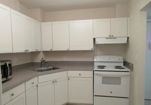 a kitchen with white cabinets and white appliances