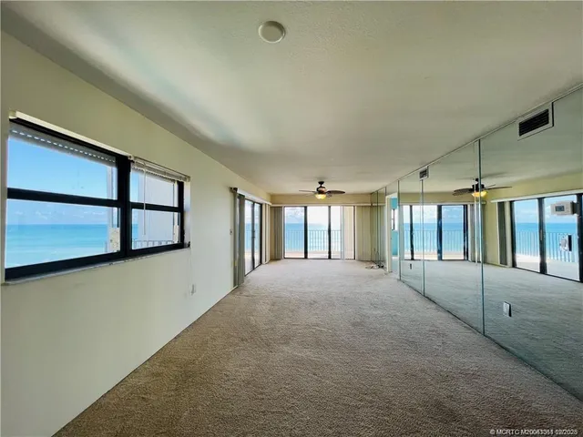 a big room with windows and chandelier fan