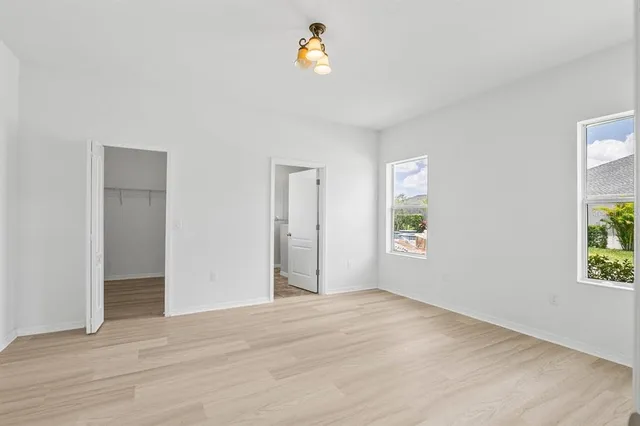 a view of an empty room with window and wooden floor