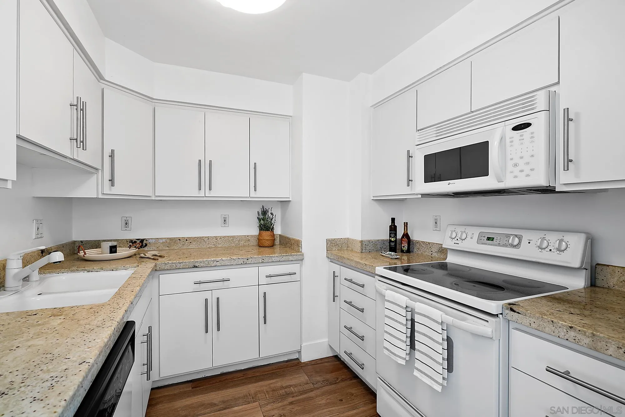 1720 Avenida Del Mundo, Unit 208 Coronado, CA 92118 - Photo 18 of 42 a kitchen with stainless steel appliances granite countertop a sink stove and microwave with wooden floor