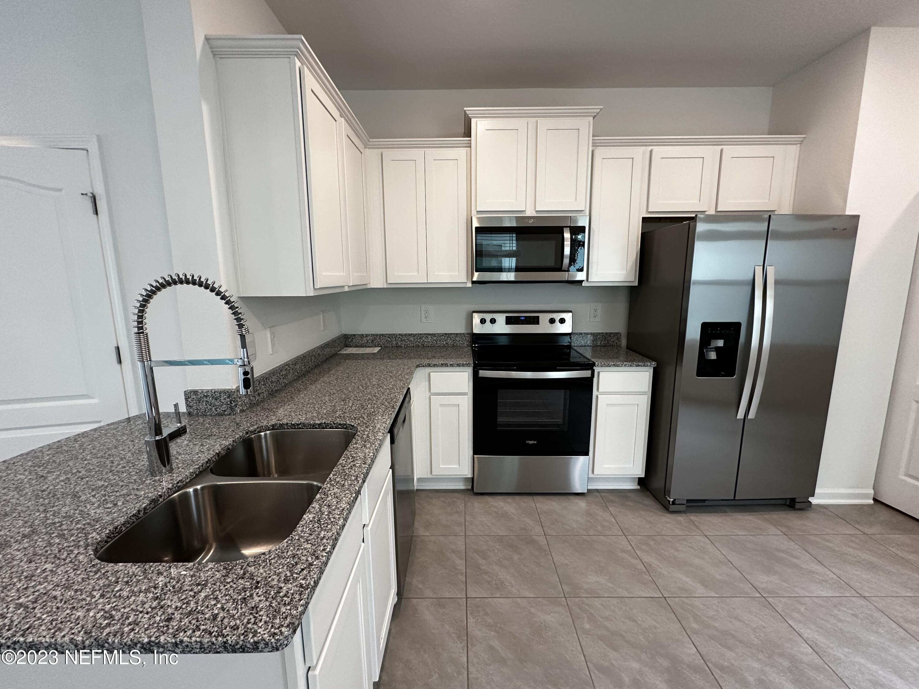 409 Talulla Trail St. Augustine, FL 32095 - Photo 27 of 58 a kitchen with stainless steel appliances granite countertop a refrigerator a sink a stove a microwave and island