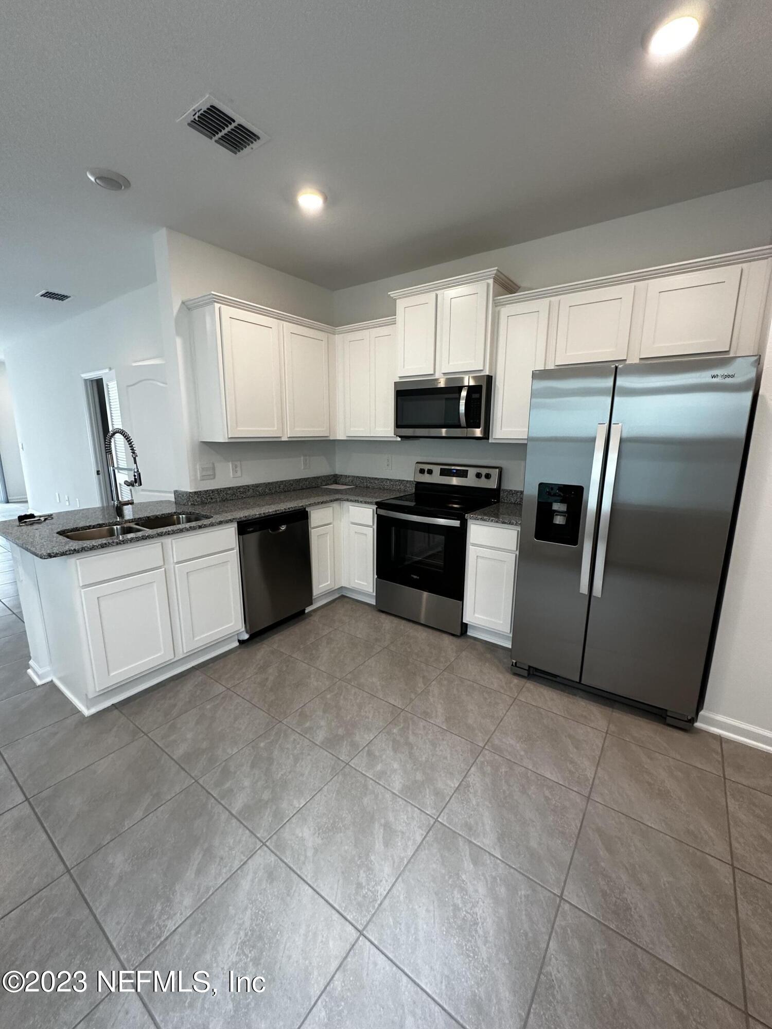 409 Talulla Trail St. Augustine, FL 32095 - Photo 32 of 58 a kitchen with stainless steel appliances granite countertop a sink stove and refrigerator