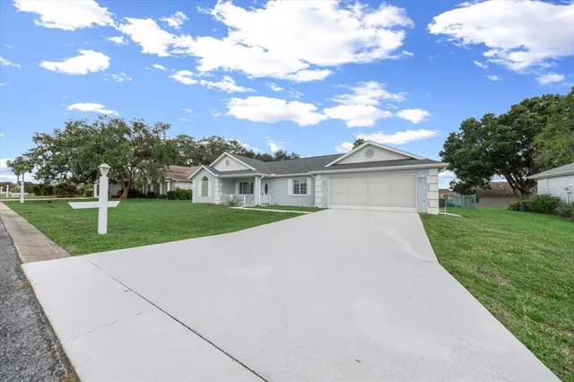 a view of a house with a big yard plants and large trees