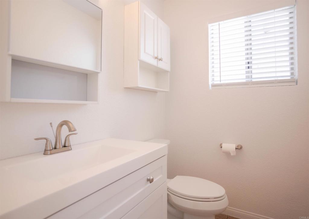 15523 Studebaker Road Norwalk, CA 90650 - Photo 58 of 59 a bathroom with a toilet a sink a mirror and a window