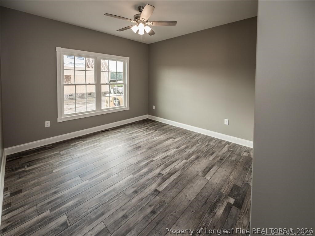 1102 West Carthage Road Lumberton, NC 28360 - Photo 32 of 41 an empty room with wooden floor chandelier fan and windows