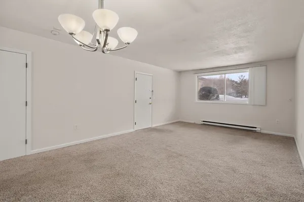 a view of an empty room with a chandelier fan