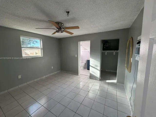 a view of a livingroom with a chandelier fan and refrigerator in a kitchen