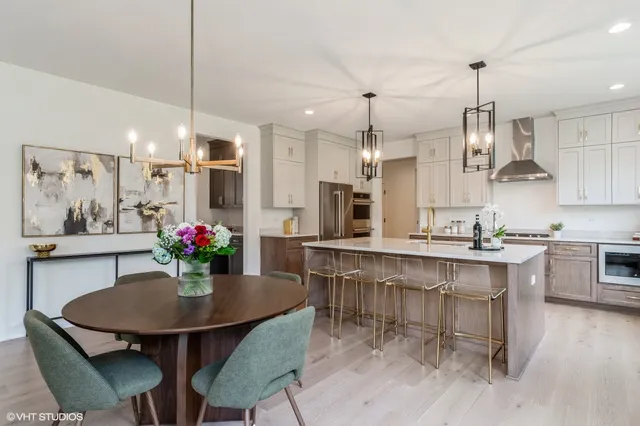a kitchen with kitchen island a dining table chairs sink and white cabinets